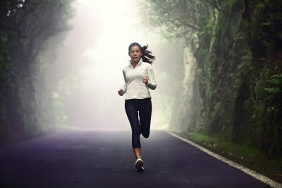 Woman running on road. Female runner jogging on mountain road tr