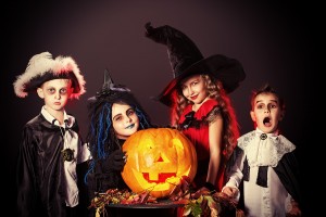 Cheerful children in halloween costumes posing with pumpkin over