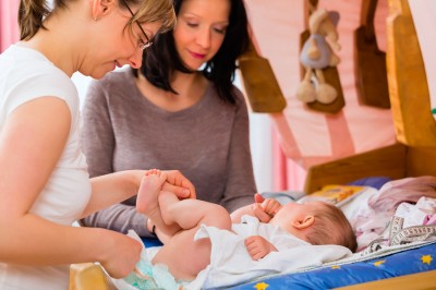 Midwife examining newborn baby at postnatal care in practice