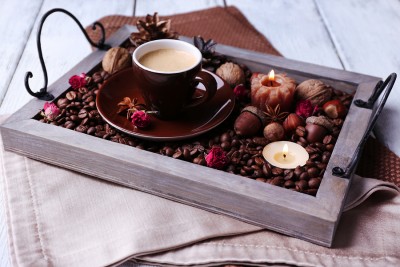 Candles on vintage tray with coffee grains and spices, cup of te