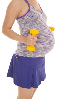a woman with her weights next to her belly wanting to be a healthy mom.
