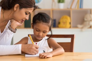 Beautiful Indian woman helping her daughter with homework