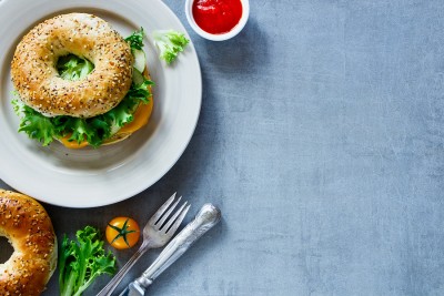 Tasty cheese sandwich on bagel with fresh vegetables over grey vintage background border top view copy space. Vegetarian and healthy eating concept. ** Note: Visible grain at 100%, best at smaller sizes