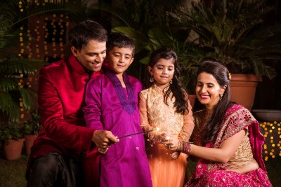 Indian Family in traditional wear playing with sparklers or phuljhadi while 