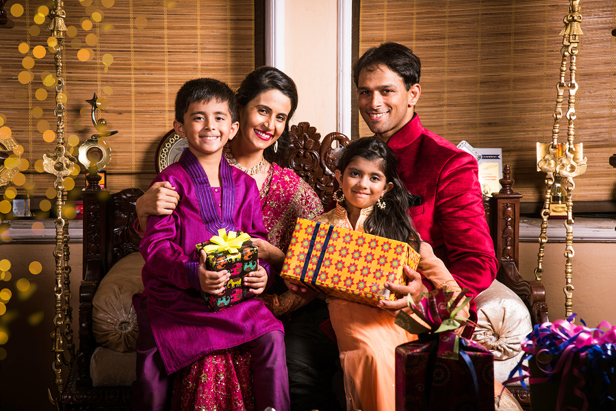 Indian family celebrating diwali festival or birthday by exchanging or showing gifts, two generations of indian family and gifts and sweets, diwali or festival or happiness concept