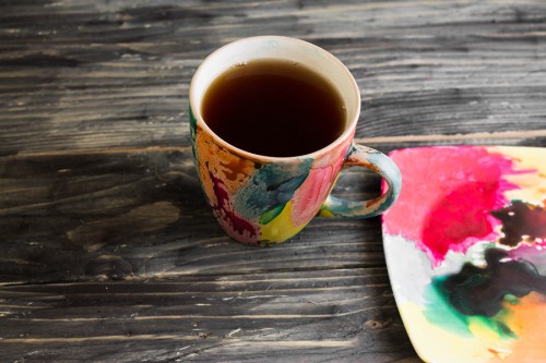 Colorful cup of tea on a wooden table in rustic style reflecting Holi