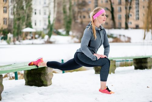it woman stretching her limbs for sports exercise in winter