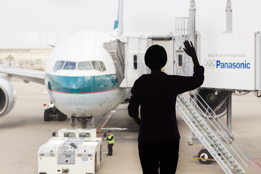 Silhouette Of A Woman Waving Goodbye To An Airplane