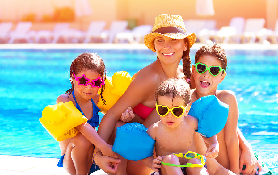 Happy big family having fun at the pool, spending summer vacatio